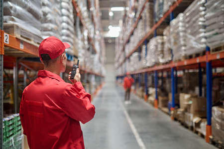 Warehouse worker communicating with his colleague over the walkie-talkieの写真素材