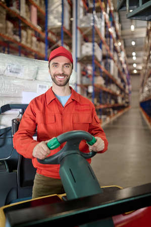 Cheerful worker moving merchandise around the storehouse