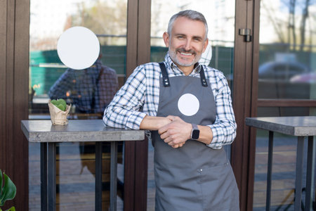 Cafe owner standing near the table outside and looking happyの写真素材