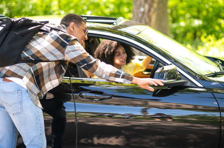 Young man on the road flirting with a female driver while asking the wayの写真素材