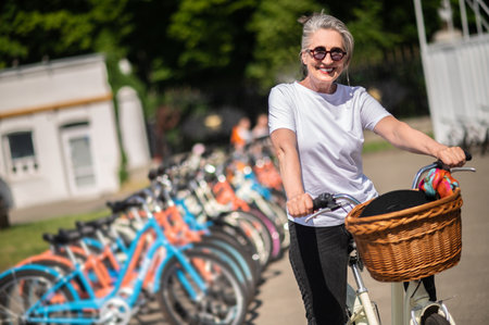 Happy mature woman with a basket on a bikeの写真素材