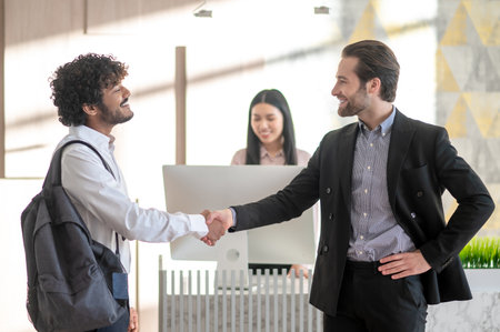 Young manager welcoming new employee and looking positive