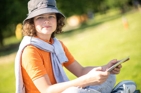 Calm adolescent with his gadget sitting outdoorsの写真素材
