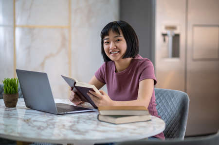 Pretty young asian girl reading a book and looking involved