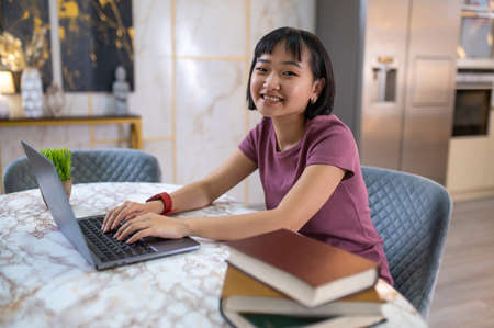A smiling young girl sitting at the laptop