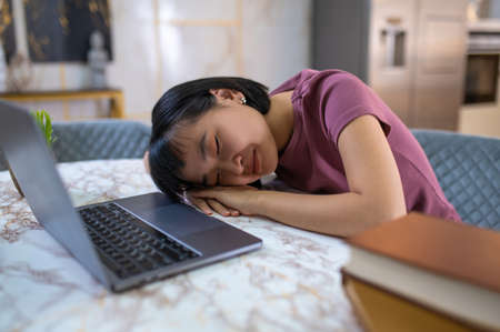 A cute dark-haired girl napping after long studying