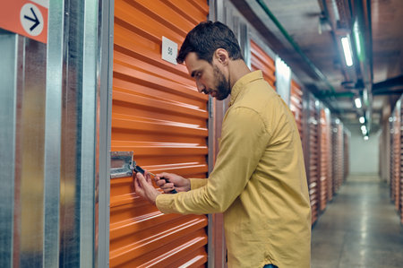Concentrated young man padlocking the storage unit doorの写真素材