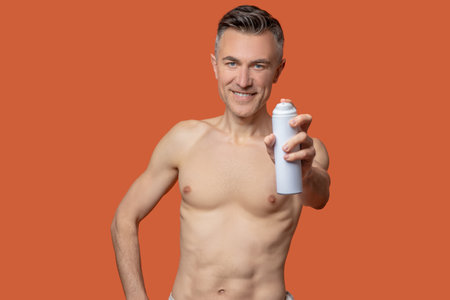 A mid aged man with a deo spray looking cheerful after showerの写真素材