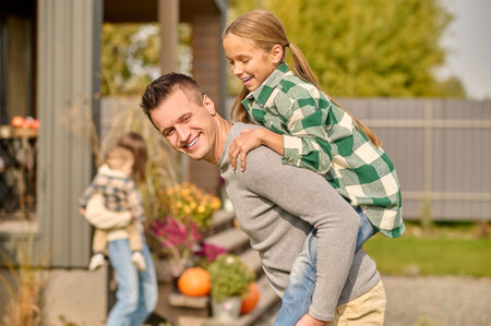 Loving young father giving his daughter a piggyback ride outdoors