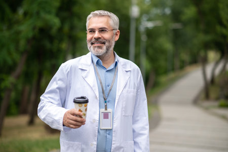 Bearded mature man in na lab coat with a cup of coffeeの写真素材