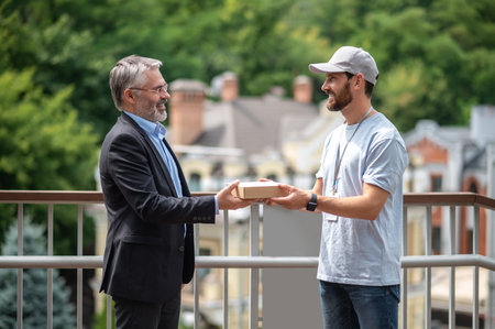 Mature businessman meeting the courrier from the delivery service