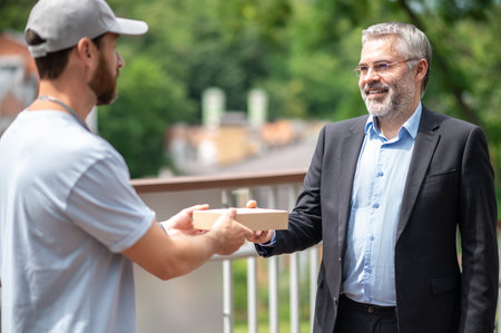 Mature businessman meeting the courrier from the delivery serviceの写真素材