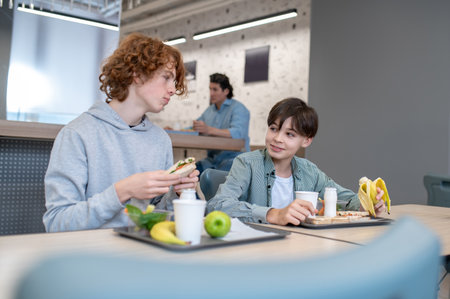 Two pupils eating lunch in the school canteenの写真素材