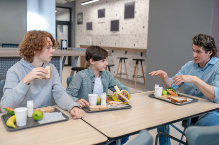 Pupils communicating with their schoolteacher at lunchの写真素材