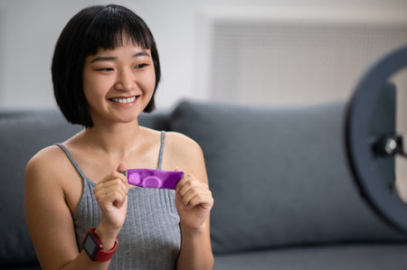 Smiling video blogger demonstrating a skincare product to the audienceの写真素材