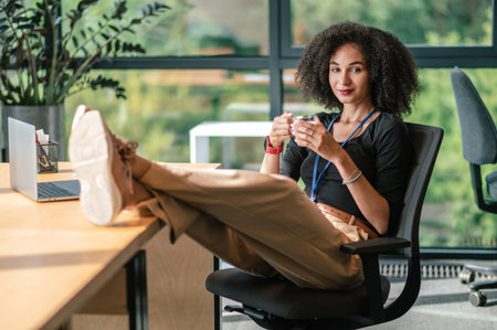 Confident sussessful businesswoman sitting in her office and having coffeeの写真素材