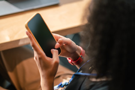 Dark-haired woman holding a smartphone in hand and typing a message