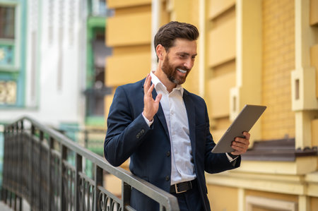 Young good-looking businessman in elegant suit with a tablet in handsの写真素材
