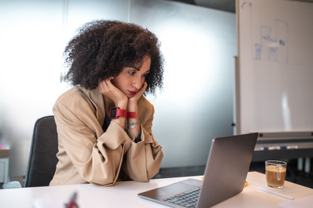 Dark-haired young woman sitting at the laptop in the office