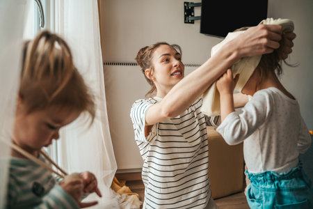 Caring female parent helping her daughter get dressed