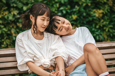 Two cute young girls resting on the bench anad feeling relaxedの写真素材