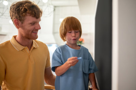 Ginger man looking busy and his kid spending time together at home