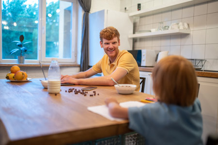Cute little boy drawing while his dad workingの写真素材