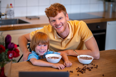 Cute kid and his father eating breakfast and talking