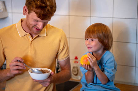 Cute kid and his father eating breakfast and talking