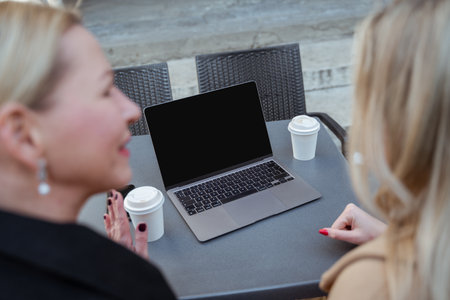 Close up of two blonde women sitting at the table in a street cafeの写真素材