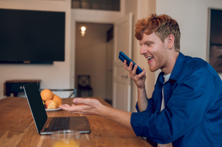 An excited man recording a voice mesage after reading good newsの写真素材