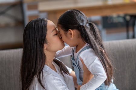 Affectionate female parent kissing her little daughterの写真素材