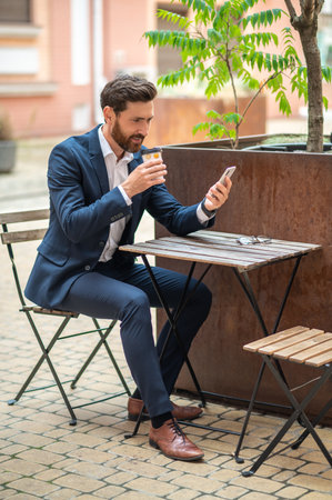 Young handsome businessman having coffee in a street cafeの写真素材