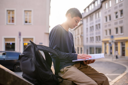Teen seated on the balustrade involved in readingの写真素材
