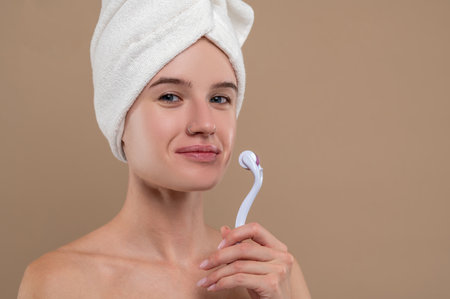 Girl holding a face roller and looking contentedの写真素材