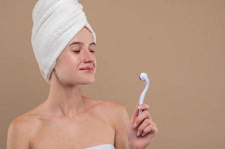Girl holding a face roller and looking contentedの写真素材