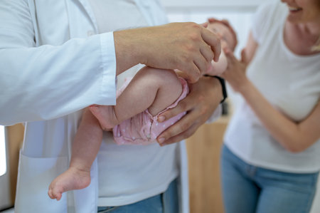 Male doctor holding a baby in hands before the medical checkの写真素材