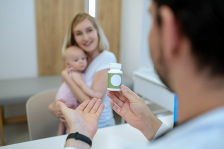 Pediatrician after check up prescribing vitamins to a young mom with a babyの写真素材