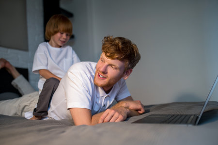 Ginger young man playing with his cute little sonの写真素材