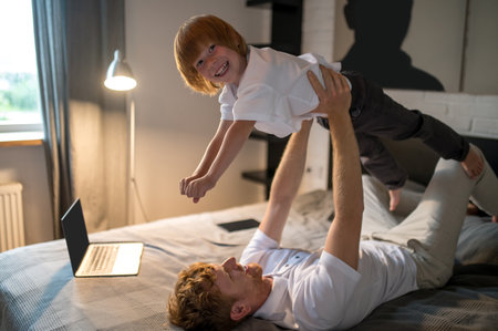 Ginger young man playing with his cute little sonの写真素材