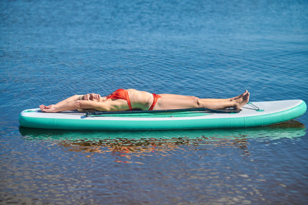 A blonde woman resting and enjoing the weather on a kayakの写真素材