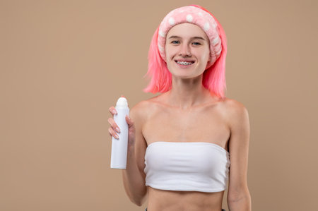 Young pinnk-haired girl holding a hair spray in handsの写真素材