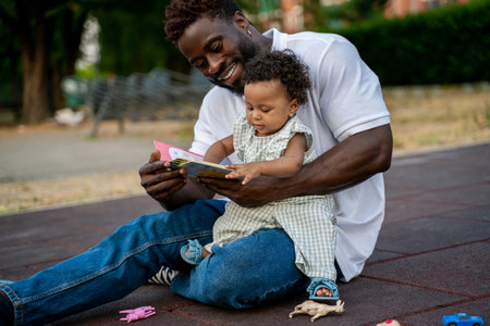 Young man teaching his daughter to readの写真素材