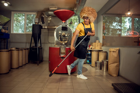 Pleased worker doing the cleaning at a coffee roasteryの写真素材