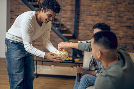 Joyous guy treating his guests with a snackの写真素材