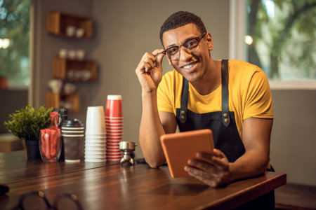Smiling happy coffee shop worker seated at the tableの写真素材