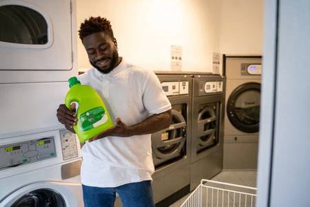 Joyous African American male standing at the launderetteの写真素材