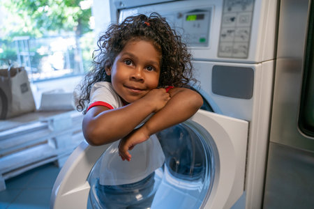Kid whiling away at a communal self-service laundromatの写真素材