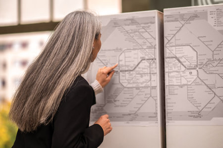 Mature woman looking for a place of destination on a map in subway