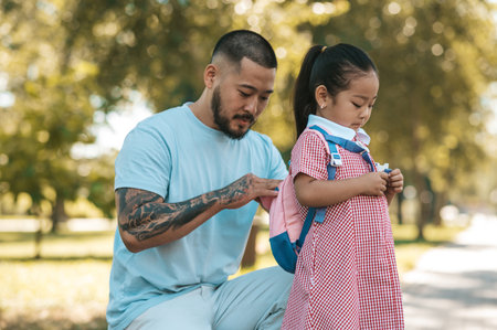 Little girl with backpack and her father in the park